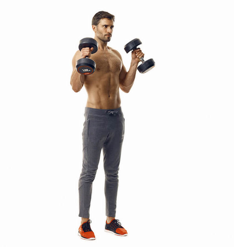 man demonstrates step two of dumbbell hammer curl; standing upright, holding a dumbbell in each hand, he bends his arms to raise the dumbbells to shoulder height