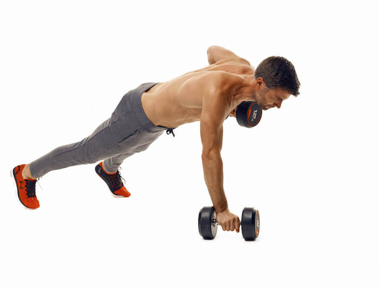man demonstrates step two of dumbbell press up renegade row; in a high plank position, one straight arm remains with the hand holding a dumbbell on the floor, while the other arm pulls the dumbbell up towards his chest