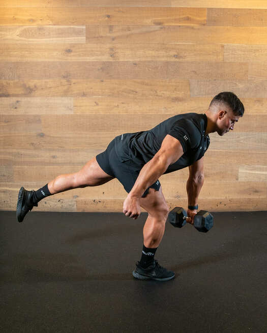 man demonstrates single leg deadlift, tilting forwards with one leg outstretched behind him