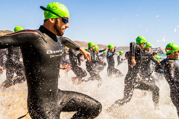 A group of male triathletes racing into the sea