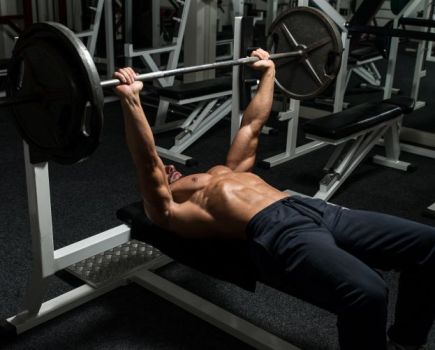 Man in gym performing barbell chest press