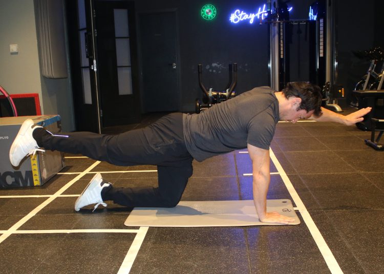 Man performing end of a bird-dog exercise - best lower back exercises