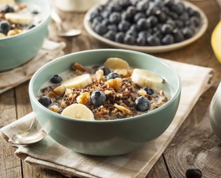 A breakfast table with bowls of cereal, blueberries and bananas