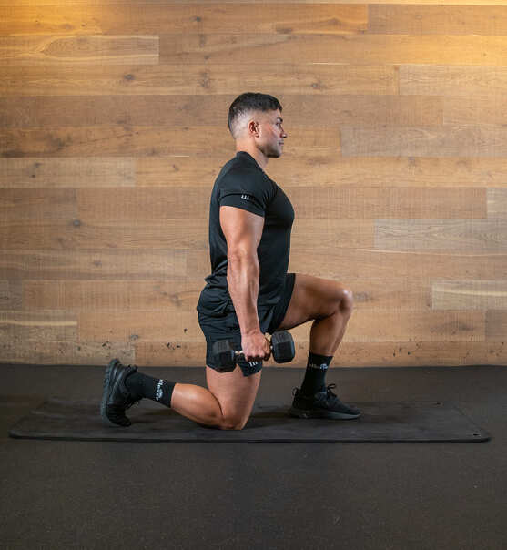 Part of the best full-body dumbbell workout: suitcase hold split squat; holding a dumbbell in each hand, man lunges with knees at 90 degrees