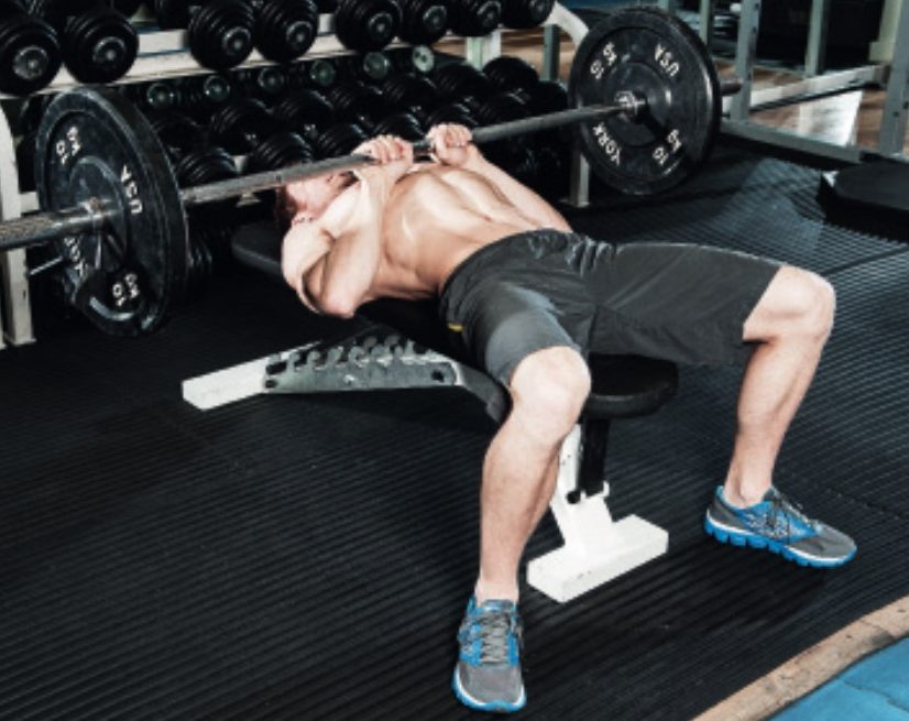 Man performing the end of the closed grip bench press - how to build bigger arm muscles