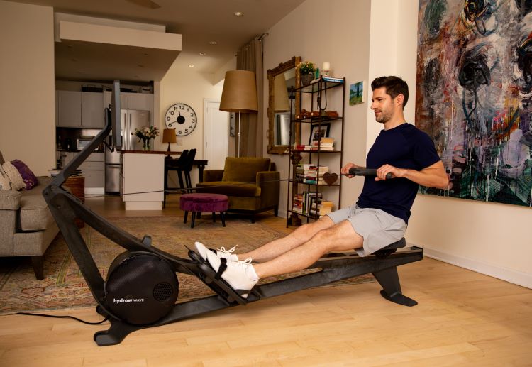 A man in an apartment using the Hydrow Wave rowing machine