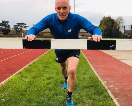 Kelsey Publishing CEO Steve Wright leans on a hurdle at a running track