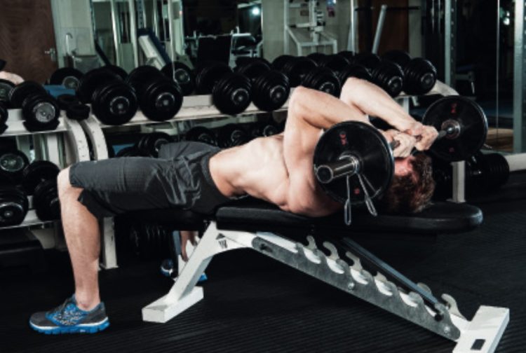 Man performing the end of the lying EZ bar triceps extension - how to build bigger arm muscles