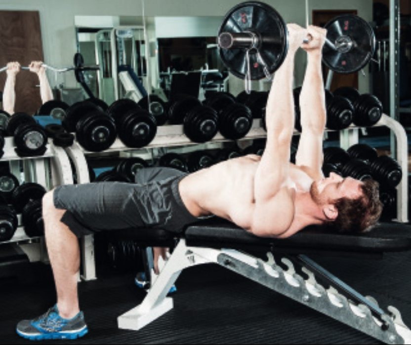 Man performing the lying EZ bar triceps extension - how to build bigger arm muscles