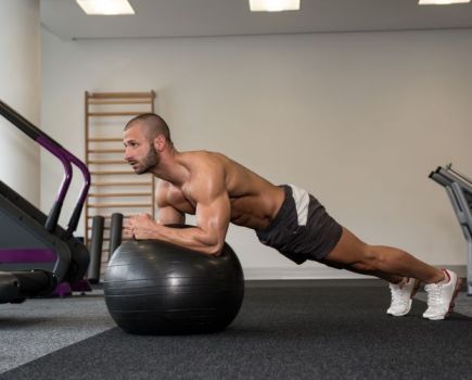 A man workout out with an exercise ball at home