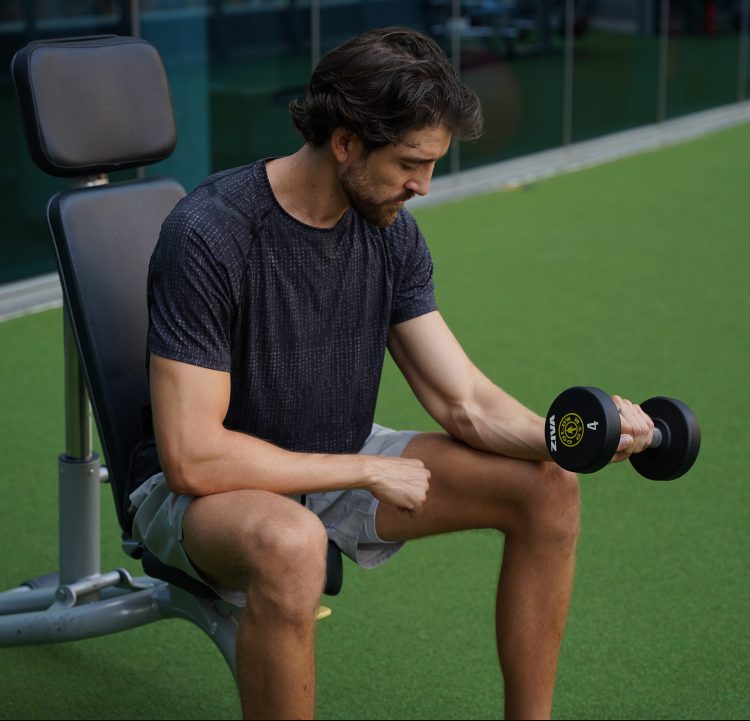 Man seated performing end of dumbbell inverted forearm curl
