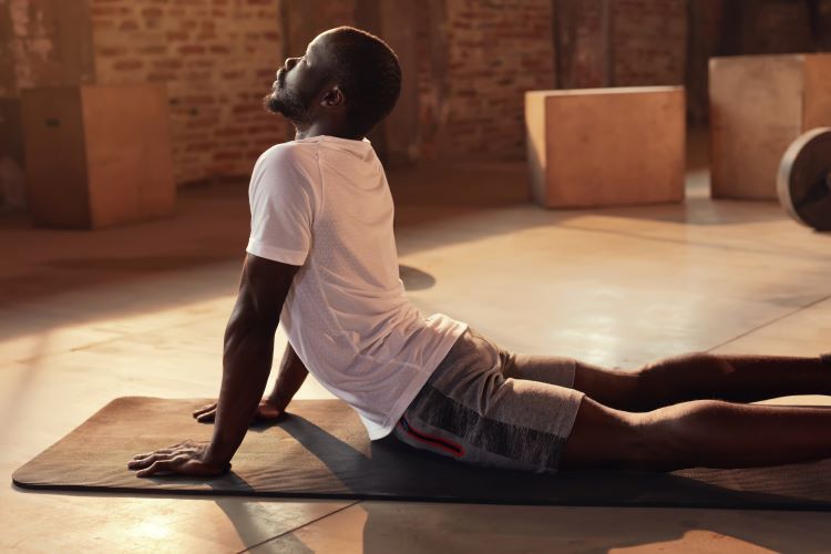 A man performing mobility back stretches on an exercise mat