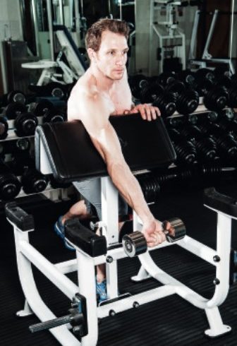 Man performing the single arm preacher curl - how to build bigger arm muscles