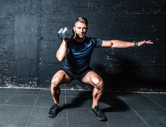 man performing single-arm dumbbell thruster learning how to get fit for summer