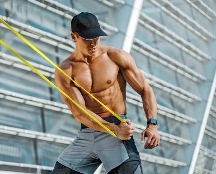 Athletic man performing exercise with resistance band