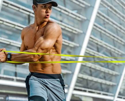 topless man showing how to use resistance bands