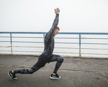 Athletic man in compression clothing stretches on a bridge before running