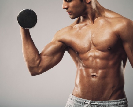 topless man using dumbbell in workout to target his abs