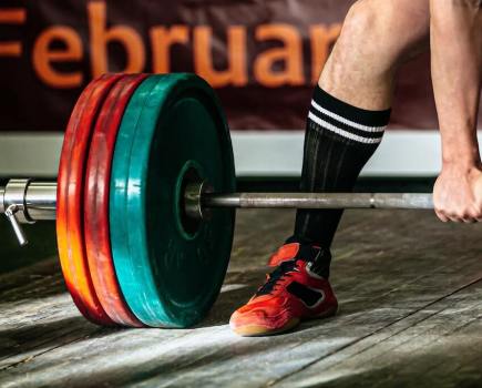 One end of a loaded barbell next to a powerlifter's foot as he's about to lift the weight