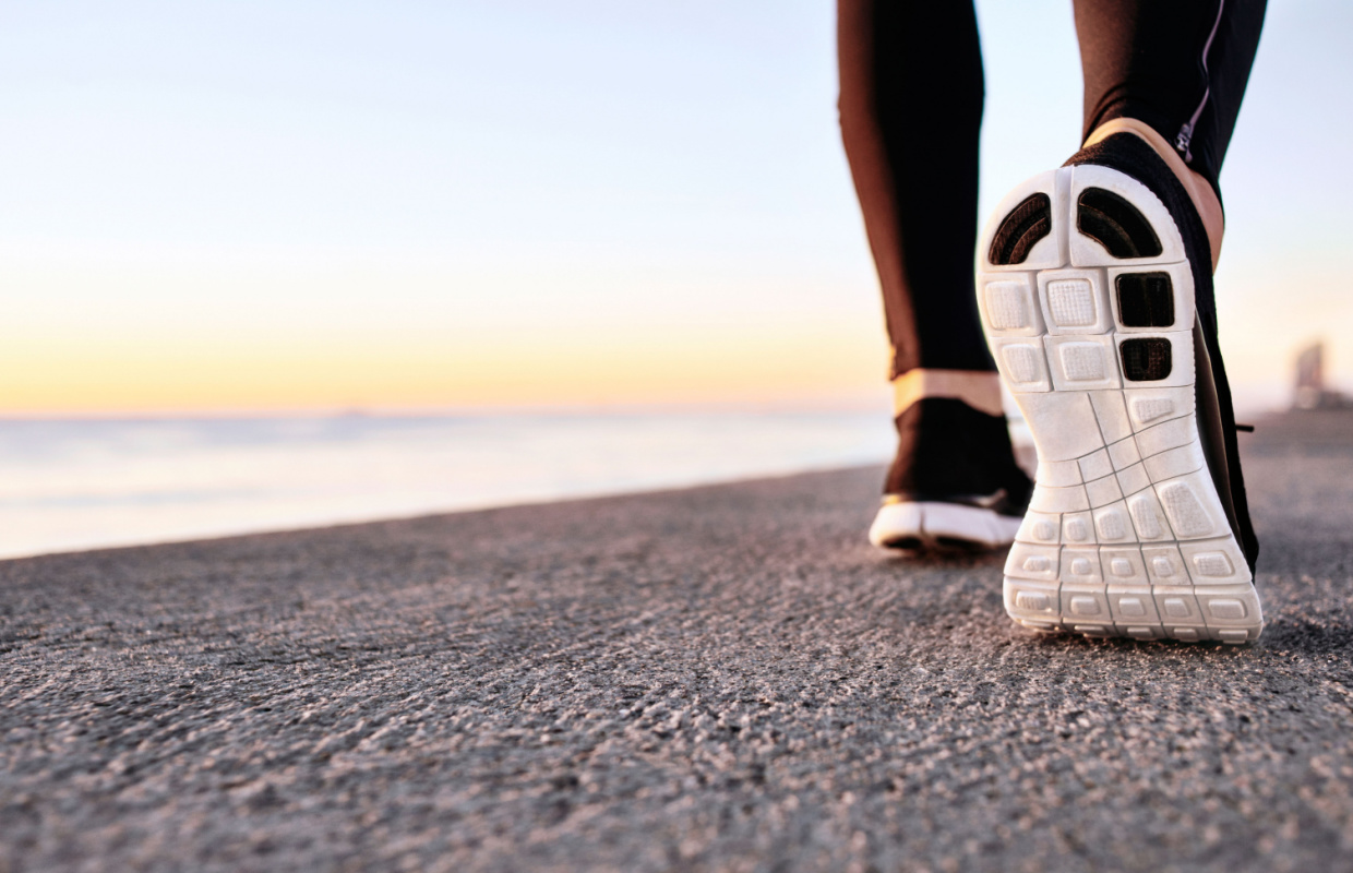 close up of man's trainers as he walks by the sea, he is learning how to walk to lose weight