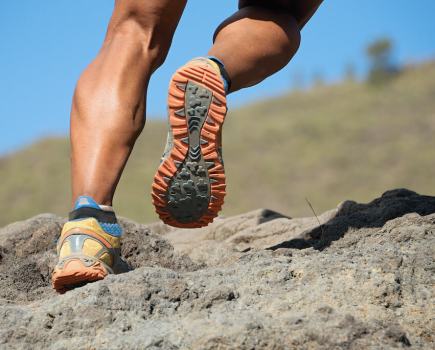 close up of man running over rocky terrain in trail shoes