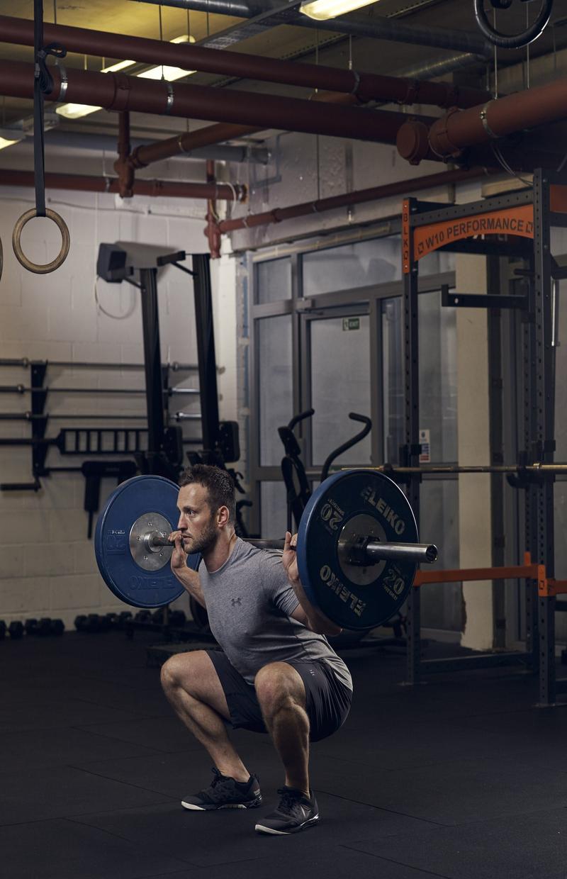 man demonstrating barbell squat in full body workout